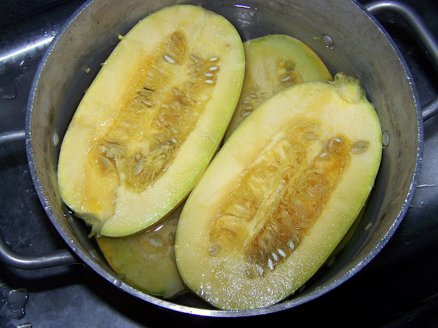 Spaghetti squash halved and boiling in a large pot