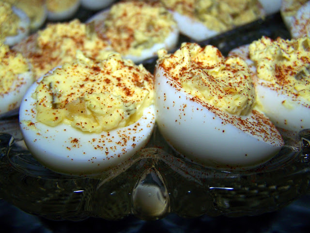 Deviled eggs topped with paprika on a cut glass egg plate